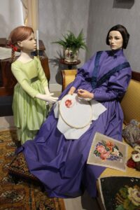 Display mannequin broidering scene in Biedermeier interior at Marela museum
